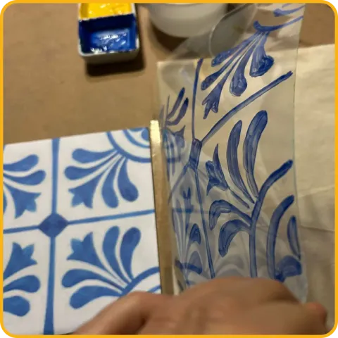 Uma folha transparente pintada com um motivo de azulejo azul, ao lado da impressão do mesmo padrão.